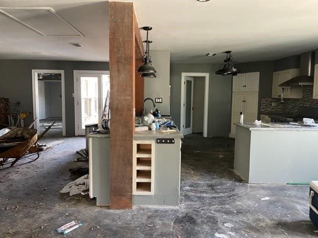 kitchen with wall chimney range hood, backsplash, decorative light fixtures, and white cabinetry