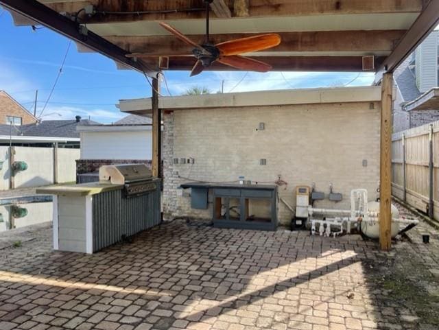 view of patio featuring exterior kitchen, a grill, ceiling fan, and fence