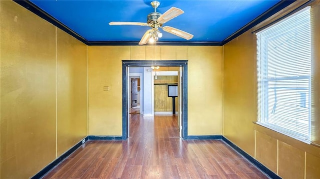 unfurnished room with baseboards, a ceiling fan, crown molding, and wood finished floors