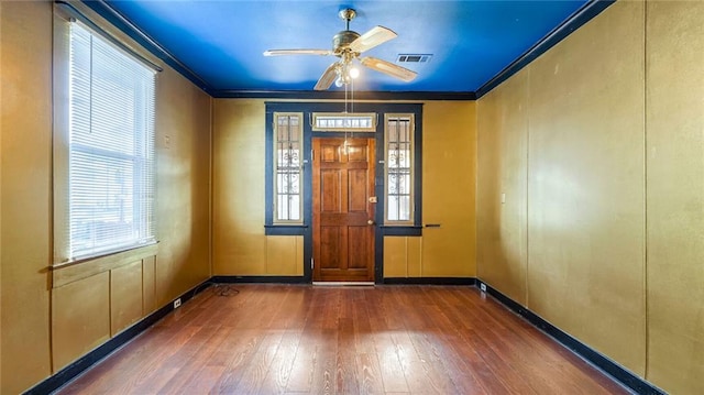 empty room featuring hardwood / wood-style floors, ornamental molding, plenty of natural light, and visible vents