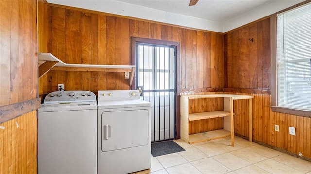 laundry area with independent washer and dryer, laundry area, a healthy amount of sunlight, and wood walls