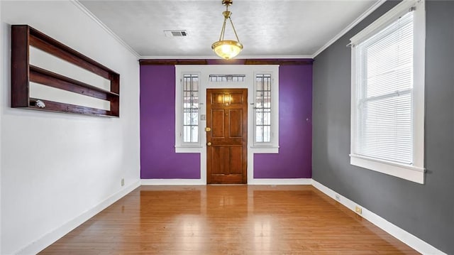 entrance foyer with ornamental molding, wood finished floors, visible vents, and baseboards