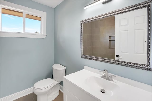 bathroom with toilet, vanity, and baseboards