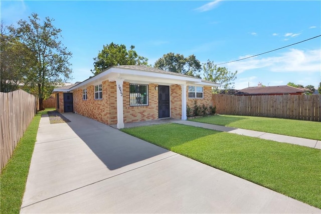 ranch-style home featuring brick siding, driveway, fence private yard, and a front lawn