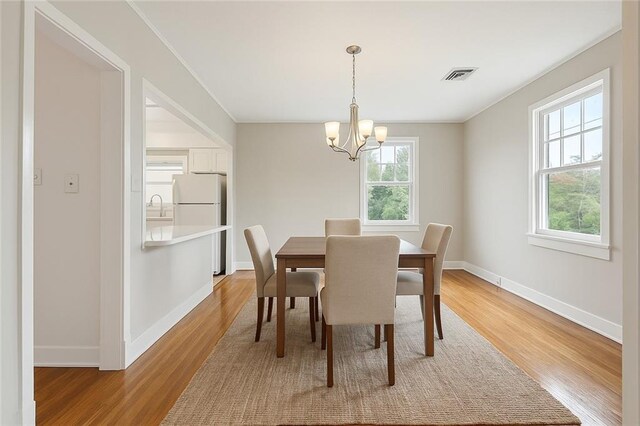 4500 S Rocheblave St, New Orleans, LA 70125 - dining area with a chandelier, light wood finished floors, and baseboards