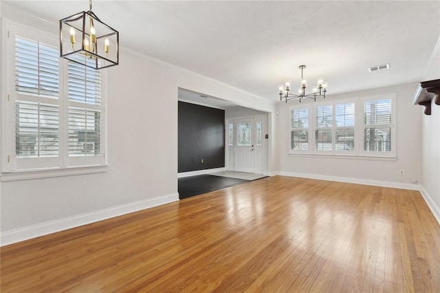 foyer featuring a notable chandelier, visible vents, ornamental molding, baseboards, and hardwood / wood-style flooring