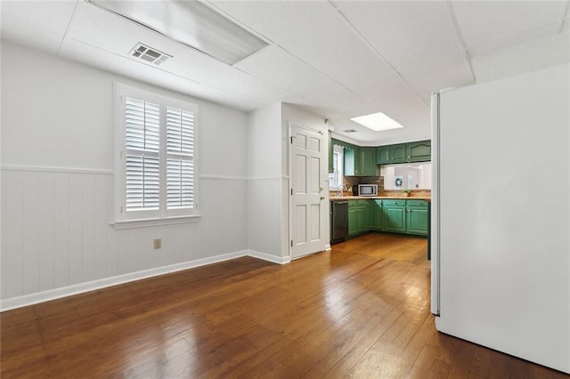 kitchen featuring dark wood-type flooring, visible vents, freestanding refrigerator, dishwasher, and green cabinetry