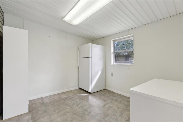 kitchen with light floors, baseboards, light countertops, and freestanding refrigerator