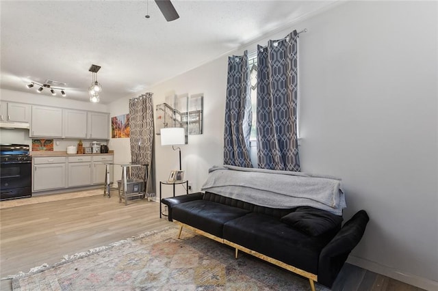 living area with light wood-style floors, baseboards, and a ceiling fan