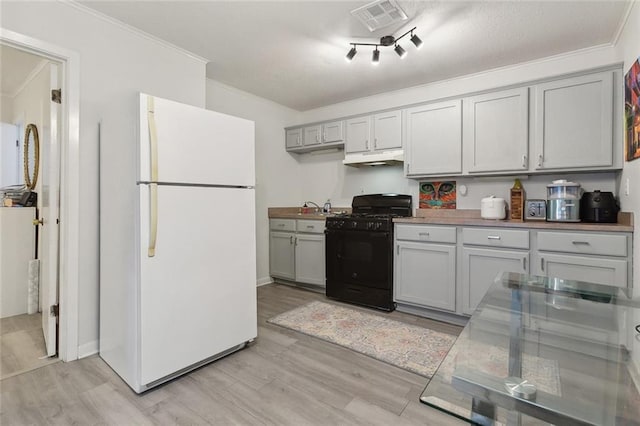 kitchen featuring visible vents, ornamental molding, freestanding refrigerator, black range with gas stovetop, and light wood-type flooring