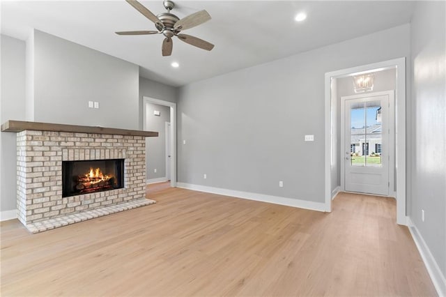 unfurnished living room featuring baseboards, light wood-style flooring, ceiling fan, a fireplace, and recessed lighting