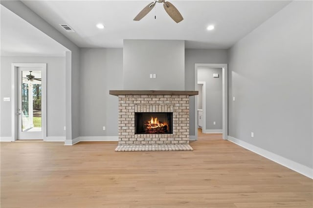 unfurnished living room featuring light wood-type flooring, a brick fireplace, baseboards, and visible vents