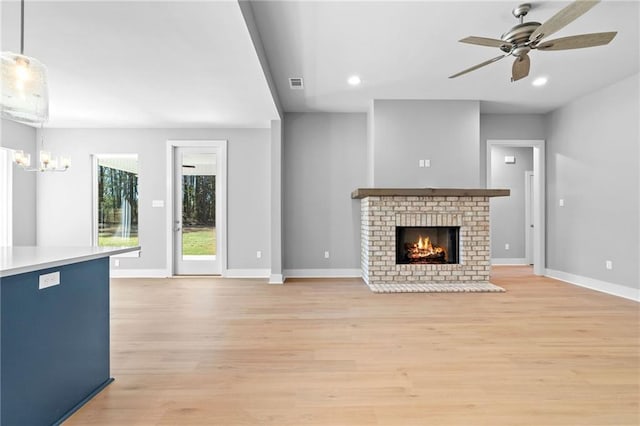 unfurnished living room featuring baseboards, visible vents, a fireplace, and light wood finished floors