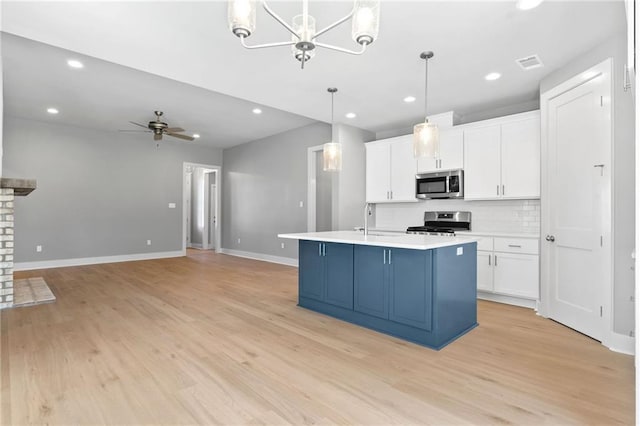 kitchen with visible vents, decorative backsplash, appliances with stainless steel finishes, a sink, and ceiling fan with notable chandelier