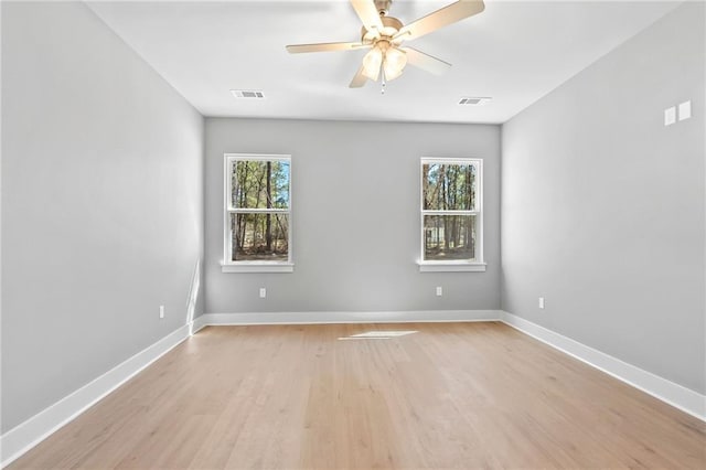 unfurnished room featuring a wealth of natural light, visible vents, and baseboards