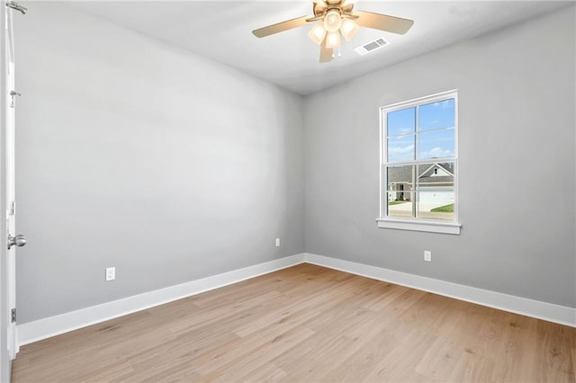 empty room featuring a ceiling fan, light wood-type flooring, visible vents, and baseboards