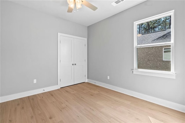 unfurnished bedroom featuring baseboards, visible vents, a ceiling fan, light wood-style floors, and a closet