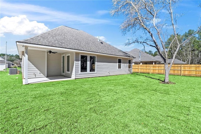 back of property featuring a lawn, ceiling fan, roof with shingles, fence, and a patio area