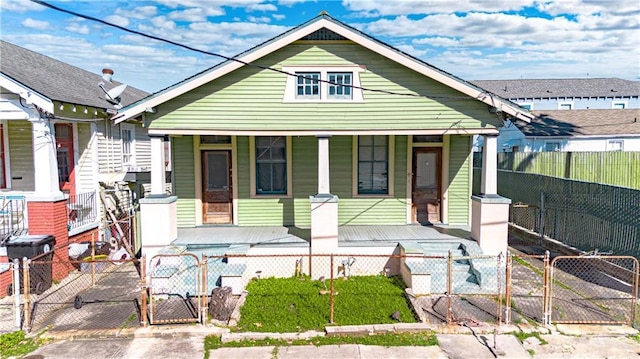 bungalow-style house featuring covered porch, a fenced front yard, and a gate