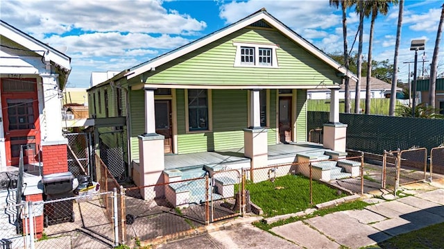 view of front of home with a fenced front yard, covered porch, and a gate