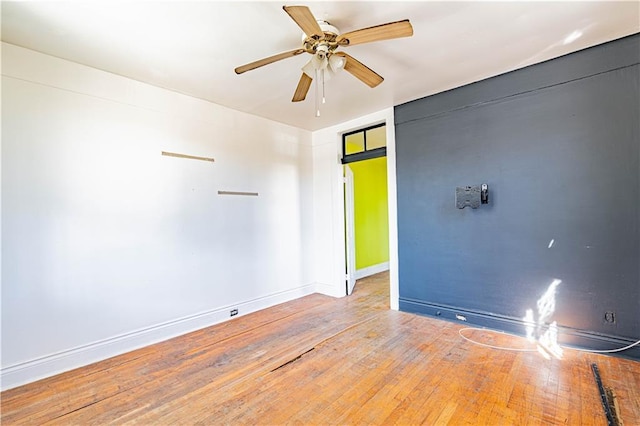 empty room with ceiling fan, wood-type flooring, and baseboards