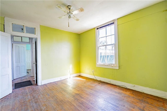 spare room featuring wood-type flooring, a ceiling fan, and baseboards