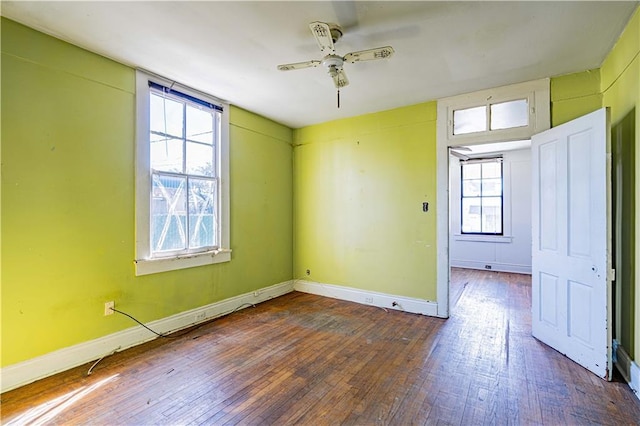 empty room featuring wood-type flooring, a ceiling fan, and baseboards