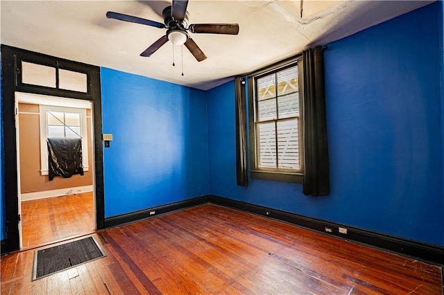 unfurnished room with hardwood / wood-style flooring, baseboards, visible vents, and a wealth of natural light