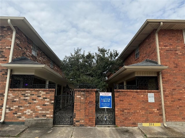 view of property exterior featuring a gate and brick siding