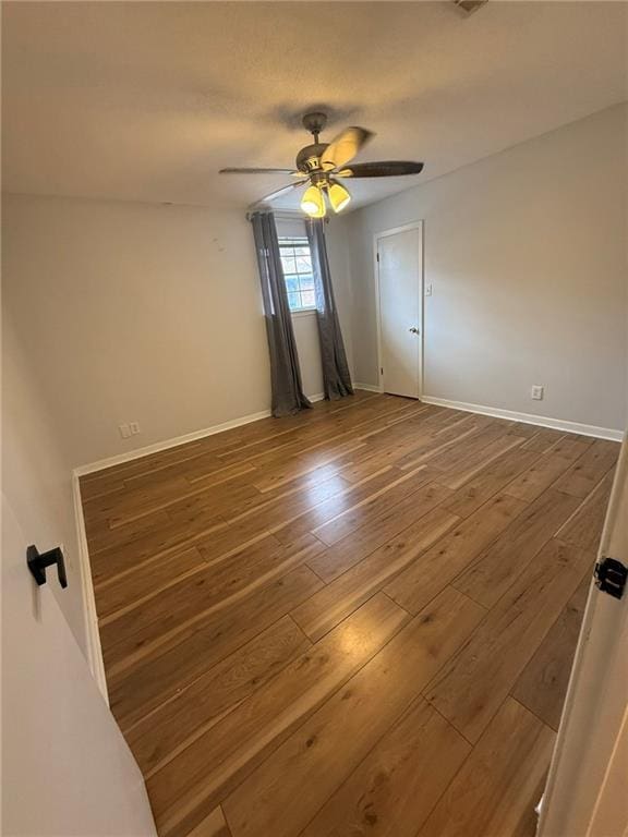 unfurnished bedroom featuring hardwood / wood-style floors, a ceiling fan, and baseboards