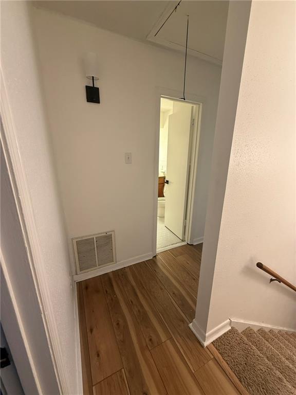 interior space with baseboards, attic access, visible vents, and wood finished floors