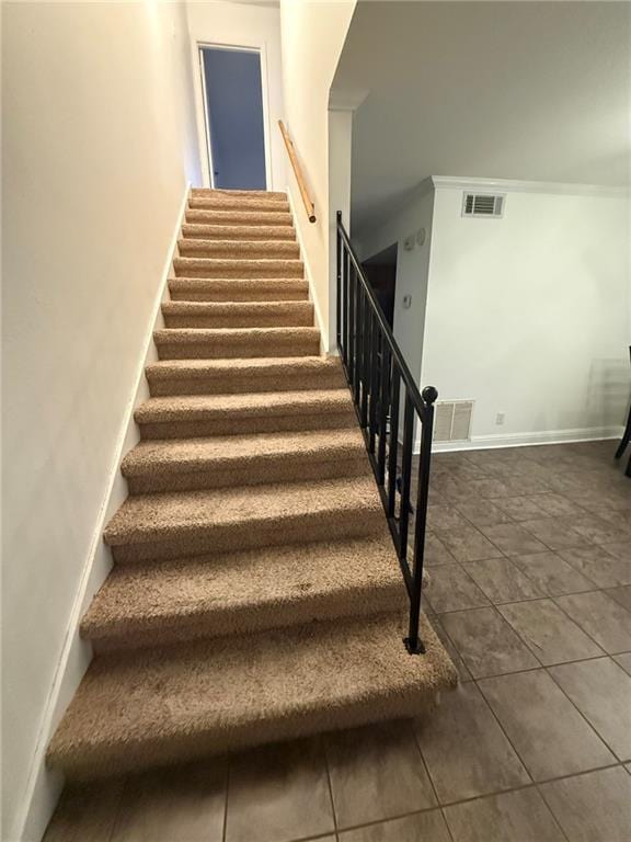 staircase with baseboards, visible vents, and crown molding