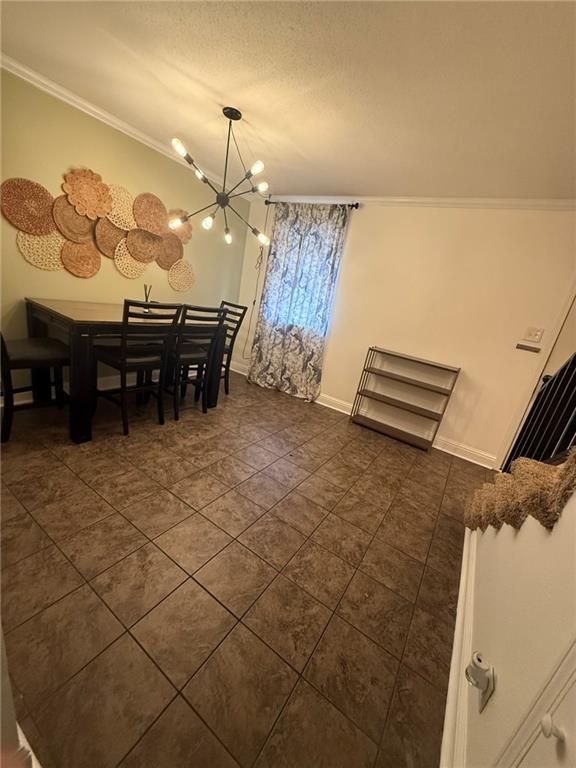 dining room with baseboards, ornamental molding, a textured ceiling, and a notable chandelier