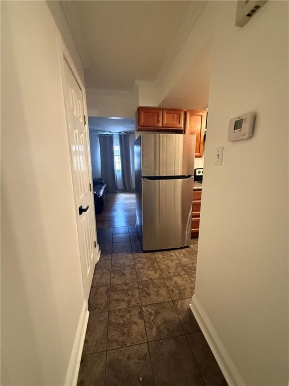 hall featuring baseboards, dark tile patterned floors, visible vents, and crown molding