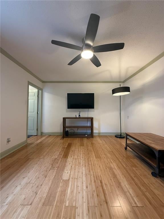 unfurnished living room featuring a textured ceiling, crown molding, light wood-type flooring, and baseboards