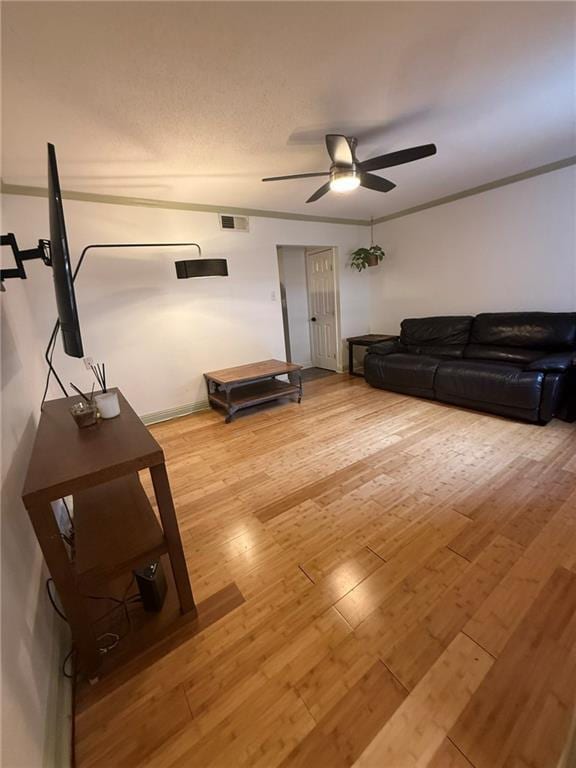 unfurnished living room with visible vents, a ceiling fan, wood finished floors, and ornamental molding