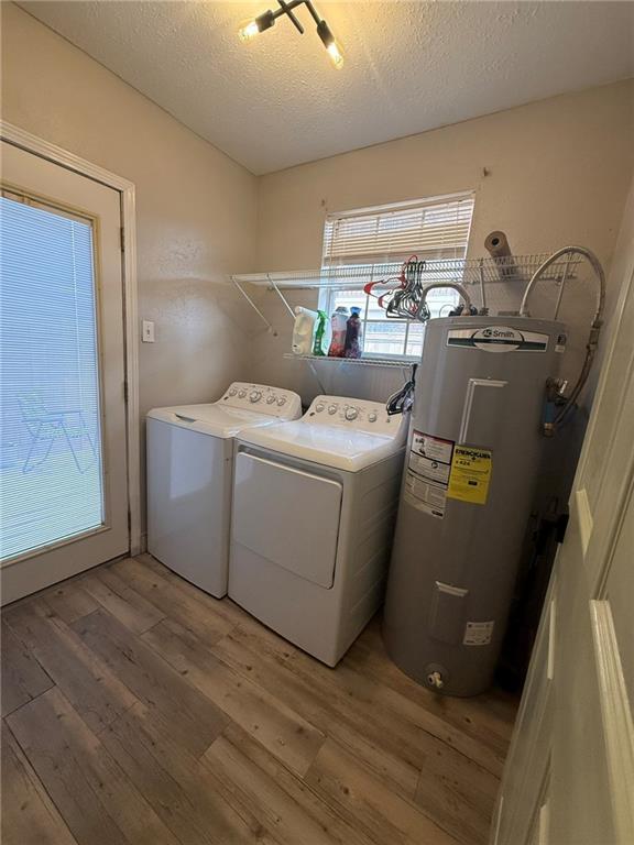 laundry room featuring laundry area, water heater, light wood-style floors, and independent washer and dryer