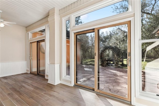 doorway to outside featuring ceiling fan, wainscoting, plenty of natural light, and wood finished floors