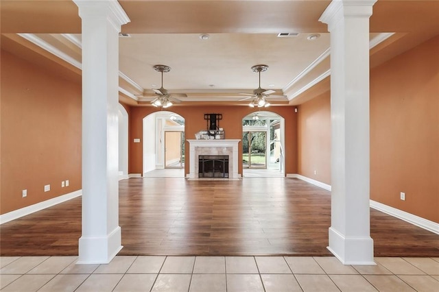 unfurnished living room featuring decorative columns, a tray ceiling, ceiling fan, and crown molding