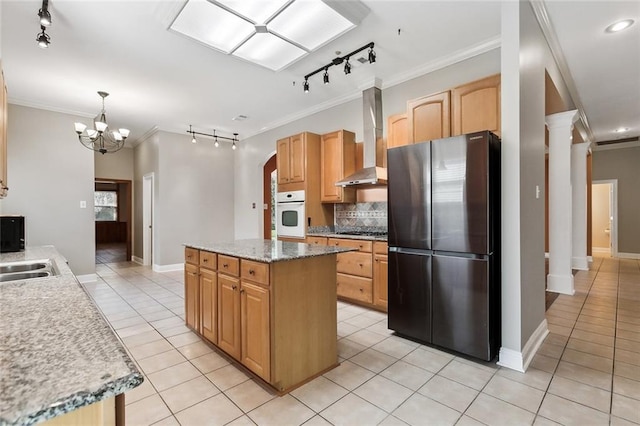 kitchen featuring stainless steel appliances, tasteful backsplash, ornamental molding, light tile patterned flooring, and wall chimney exhaust hood