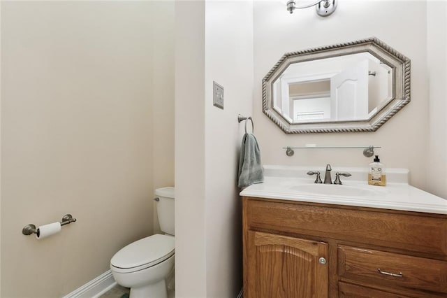 half bath featuring toilet, baseboards, and vanity