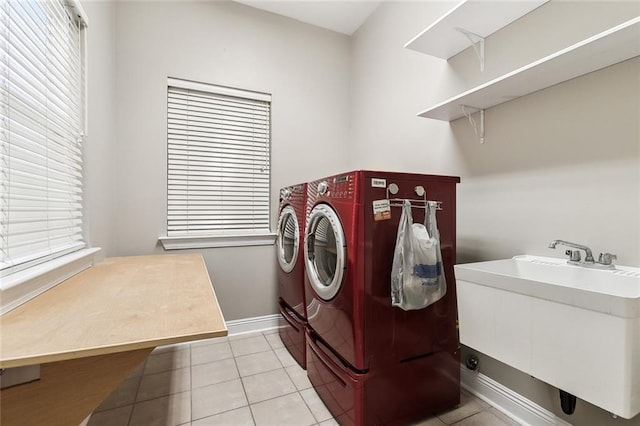 washroom featuring laundry area, light tile patterned floors, baseboards, separate washer and dryer, and a sink