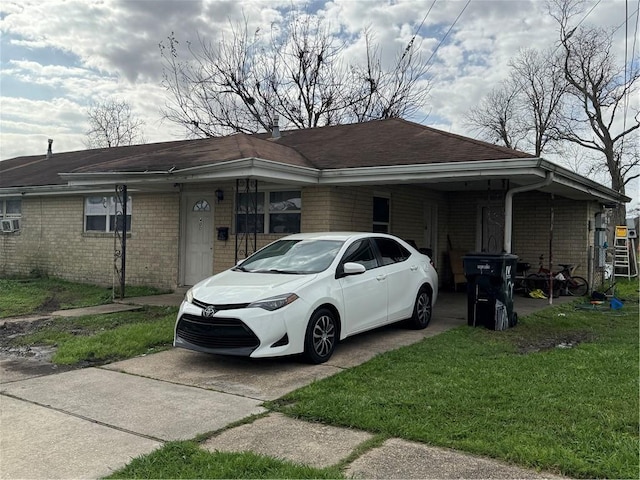 view of front facade featuring driveway, an attached carport, a front yard, and brick siding