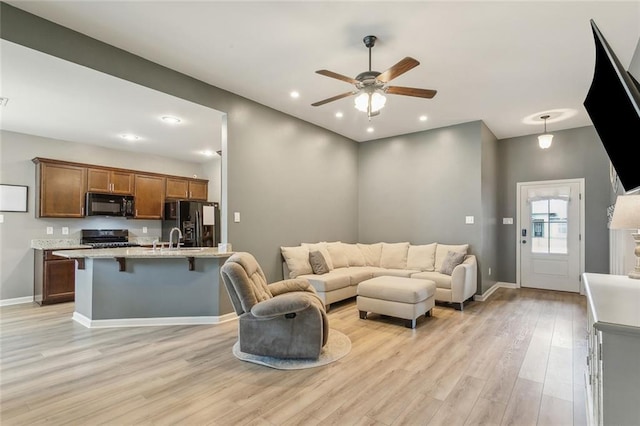 living area with a ceiling fan, recessed lighting, baseboards, and light wood finished floors