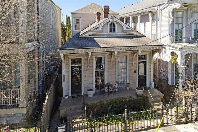 view of front facade featuring a porch, a shingled roof, fence, and a gate