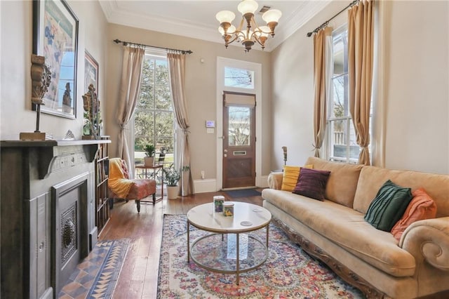 living room with a chandelier, a fireplace, wood finished floors, baseboards, and crown molding