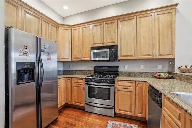 kitchen featuring appliances with stainless steel finishes, light stone counters, dark wood-type flooring, a sink, and recessed lighting