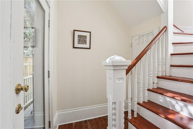 stairway with vaulted ceiling, wood finished floors, and baseboards