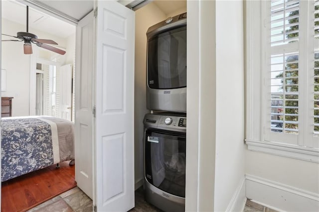 laundry room with a wealth of natural light, stacked washer / drying machine, laundry area, and ceiling fan