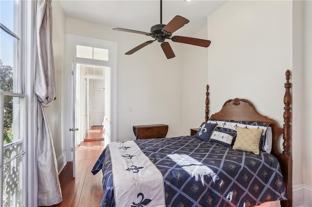 bedroom featuring ceiling fan, multiple windows, and wood finished floors